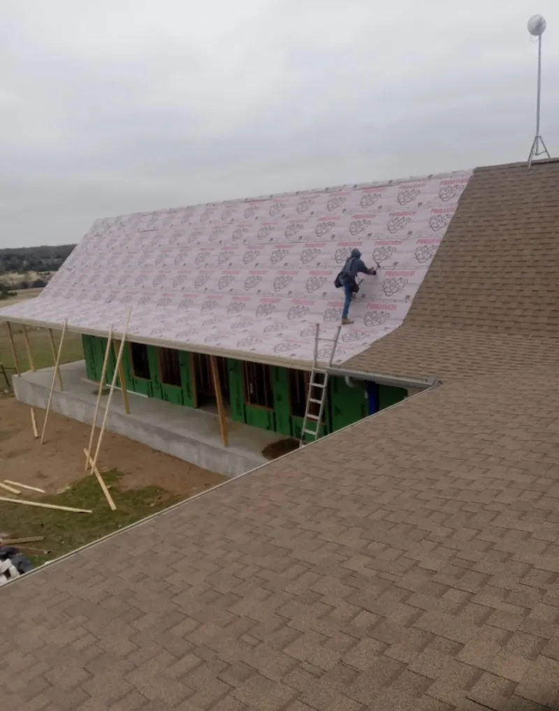 Worker preparing underlayment for a metal roof installation in Milton